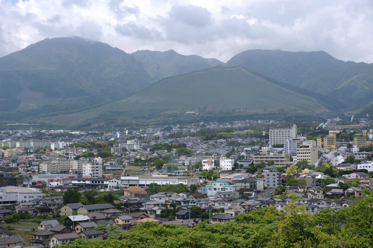 Daytime view over the Kannawa Onsen area of Beppu with green mountains behind