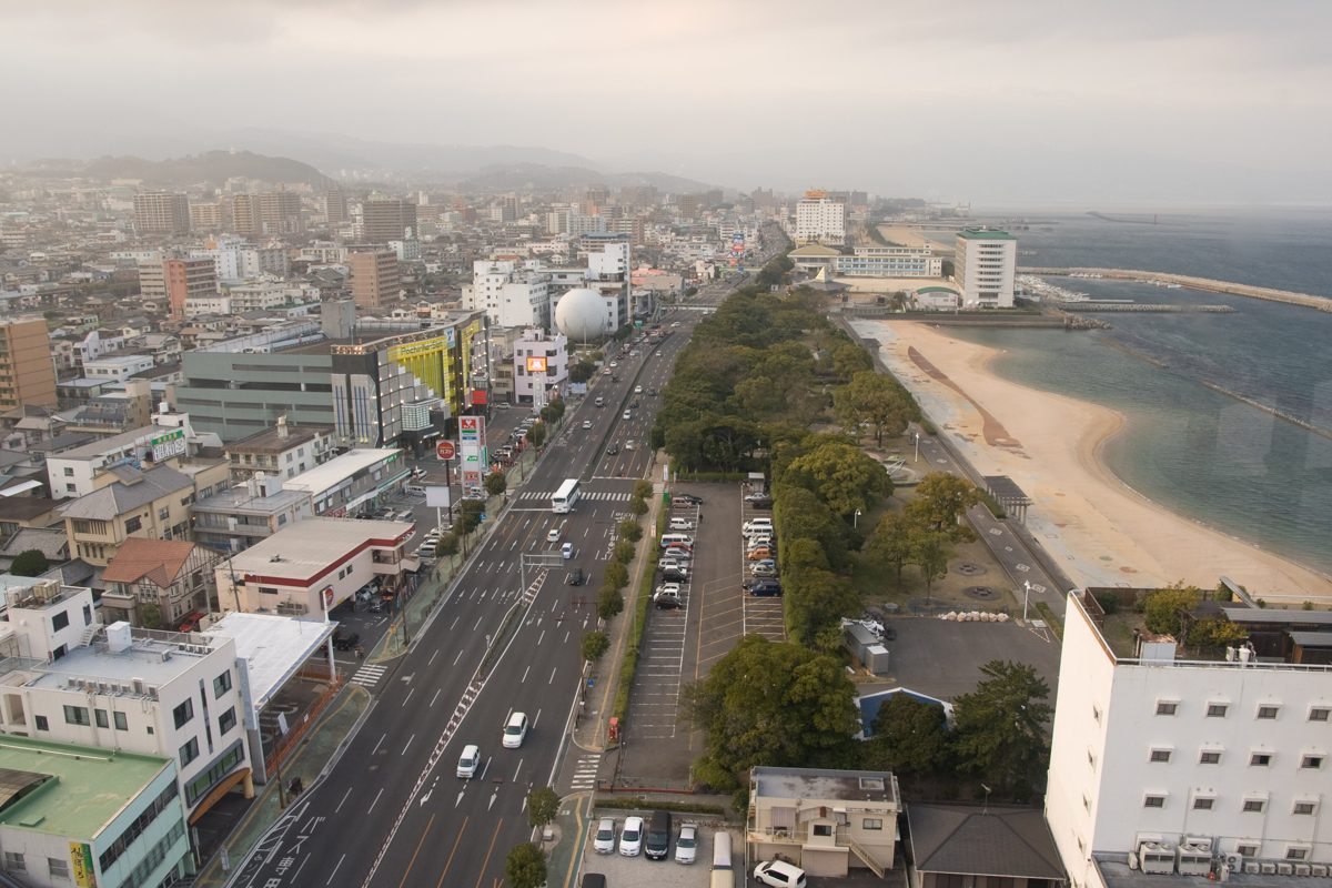 Central Beppu seen from above, with a wide road, buildings and the shore of Beppu Bay
