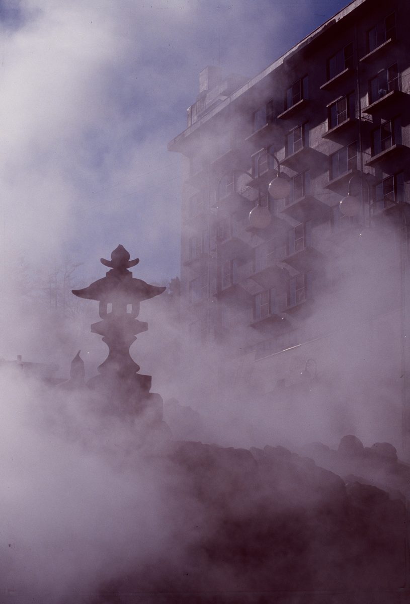 Hot spring steam rising around a stone lantern in Beppu