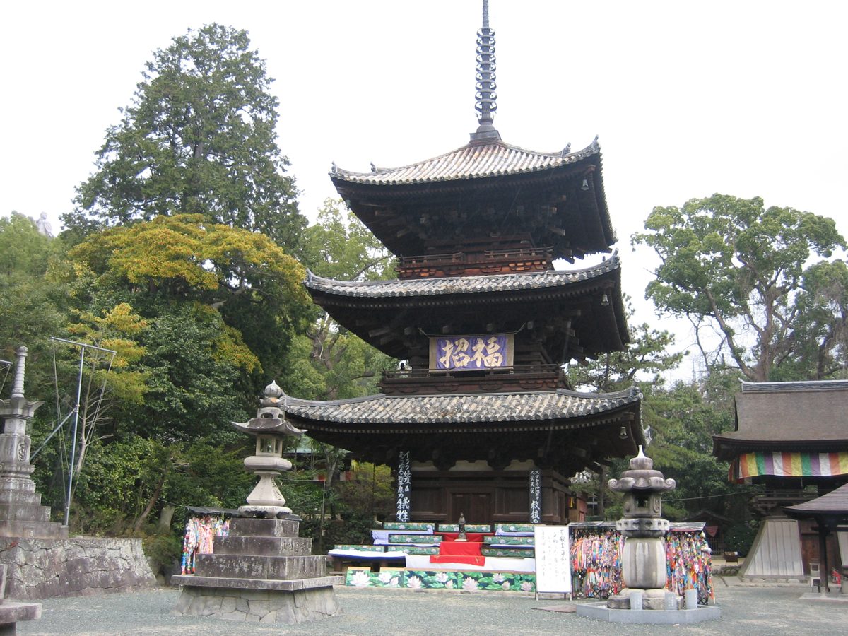 Three-storied wooden pagoda surrounded by trees at Ishiteji temple