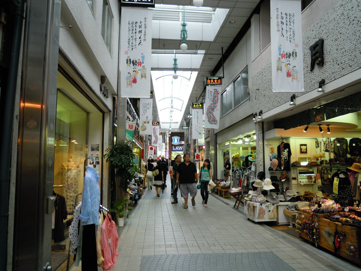 A covered shopping arcade with souvenir and clothing shops and hanging paper banners