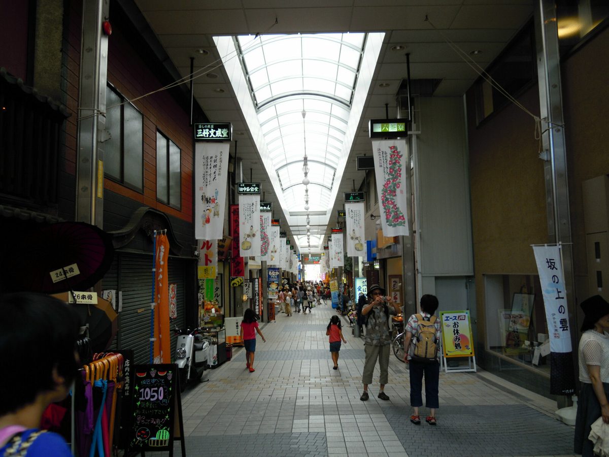 A covered shopping arcade with shops on both sides and people walking