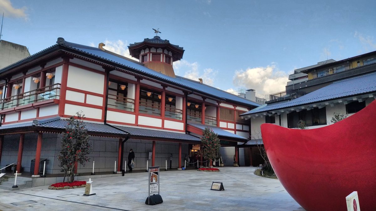 Red-and-white Asuka-no-Yu bathhouse building with a tiled roof and a small tower