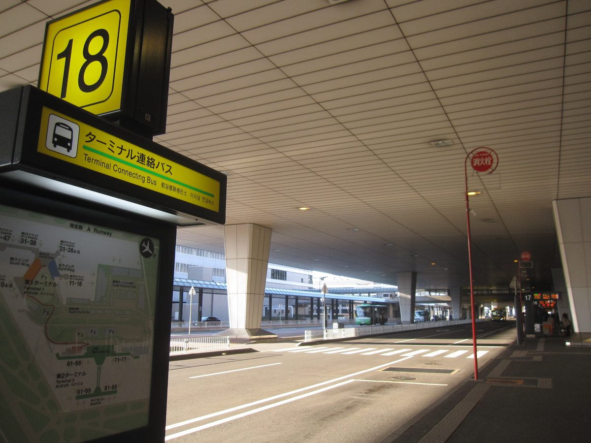 A numbered bus stop sign under a covered airport curb
