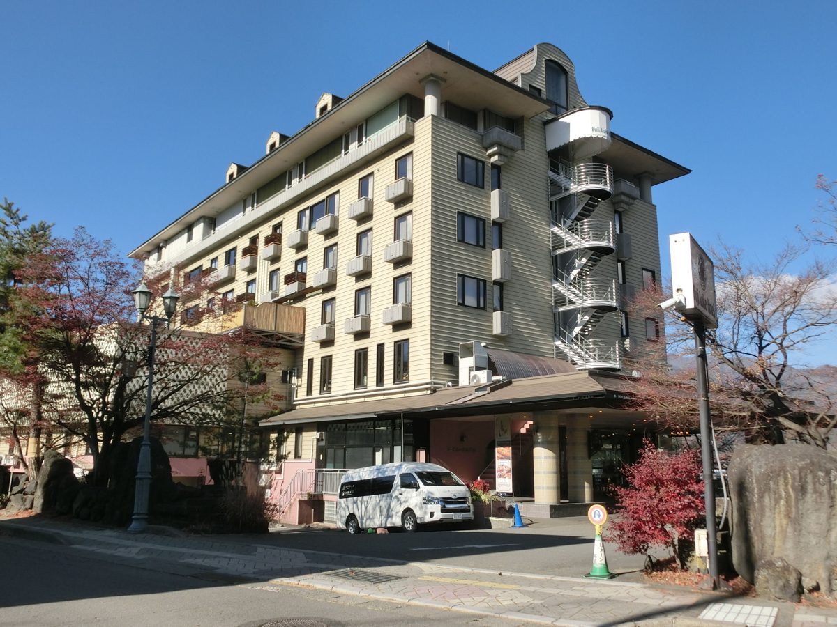 The cream-coloured multi-storey Fuji Lake Hotel building with a white shuttle van in front