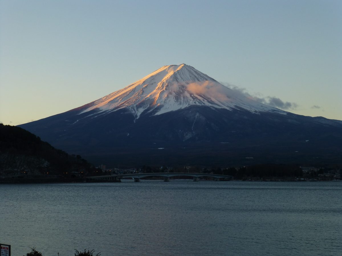 Snow-capped Mount Fuji lit pink at sunset above Lake Kawaguchi