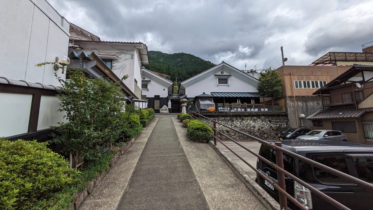 A paved walkway leading to white-walled buildings in Gero Onsen