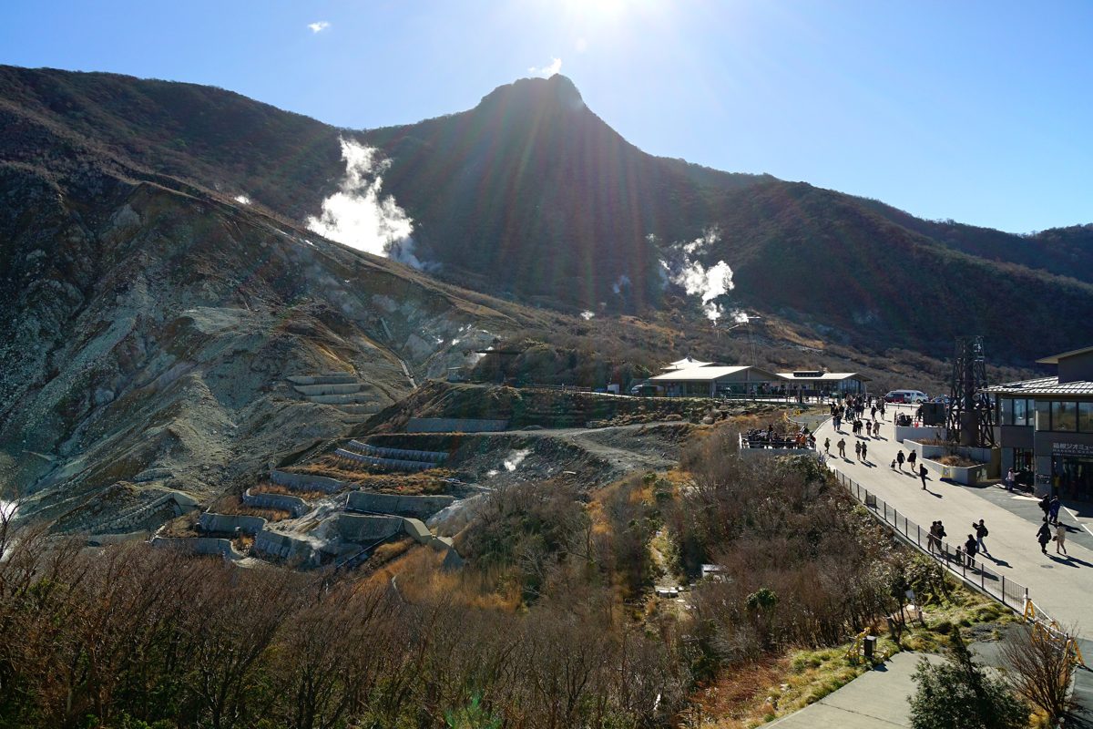 Steam rising from the volcanic slopes of Owakudani under a blue sky