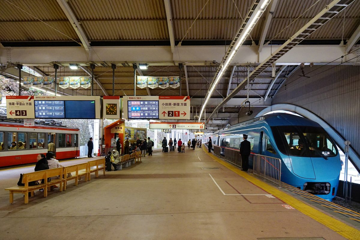 Train platform at Hakone-Yumoto Station with a blue Odakyu Romancecar and a red Hakone Tozan train