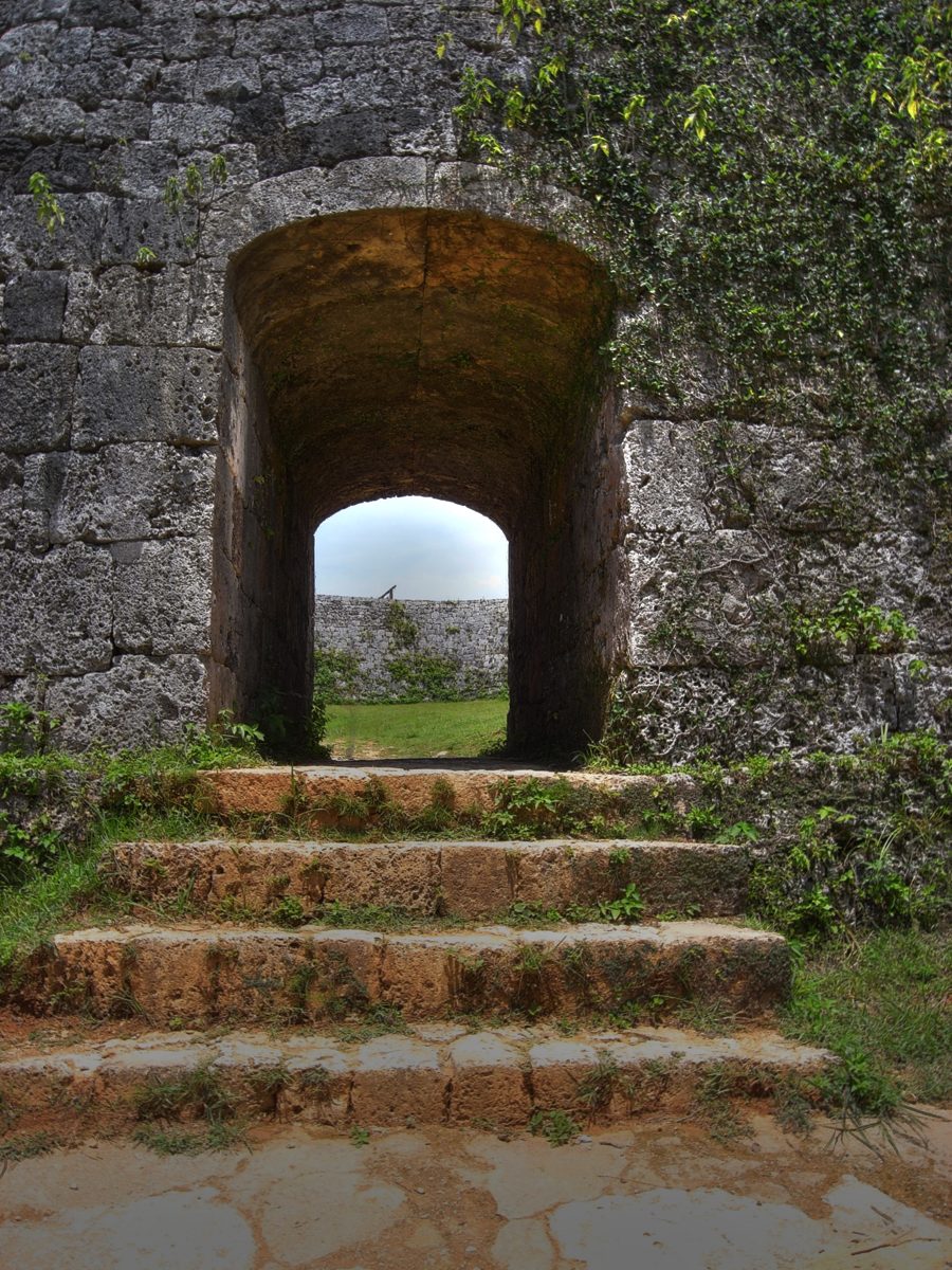 A stone archway in an old castle wall with steps leading up to it