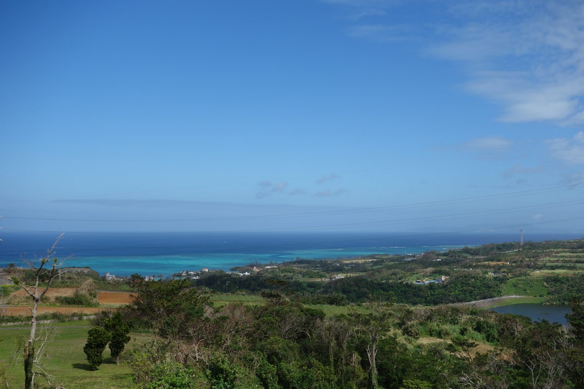 Green fields sloping down to a turquoise sea under a blue sky