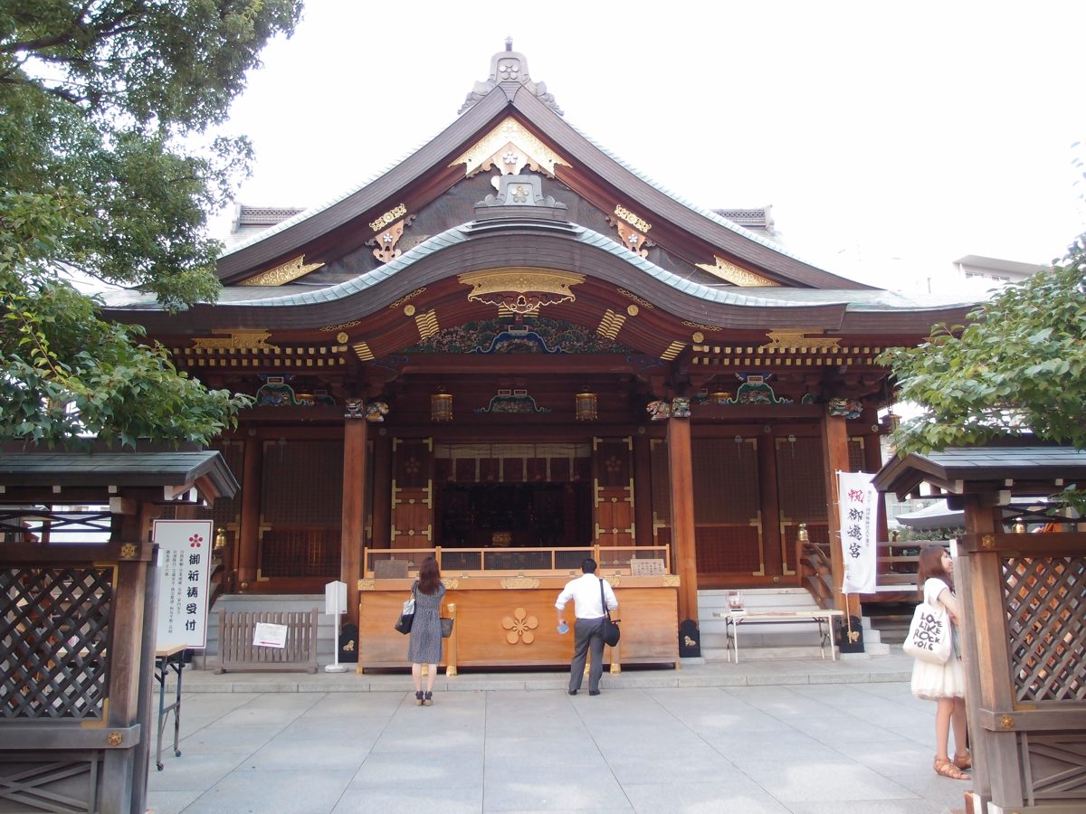 The wooden main hall of Yushima Tenjin shrine in Tokyo, with a stone-paved courtyard in front