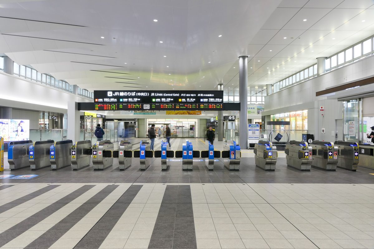 A row of automatic ticket gates in a bright station concourse