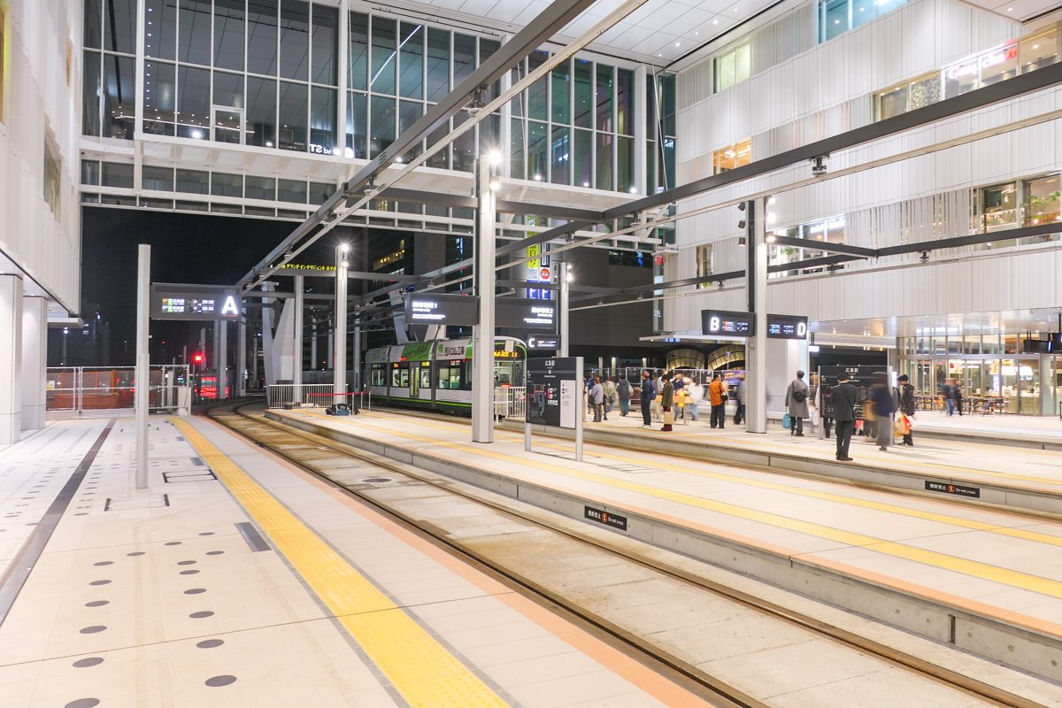 Streetcar platforms and tracks under a roof inside a modern station building