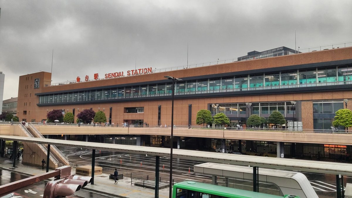 The long brick-colored front of Sendai Station with a pedestrian deck