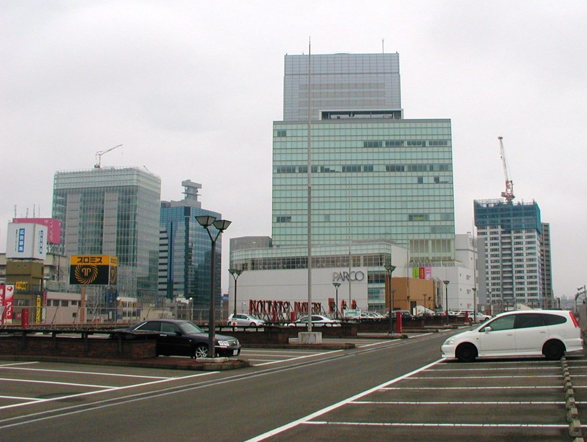 A rooftop parking lot with a few cars and office towers behind
