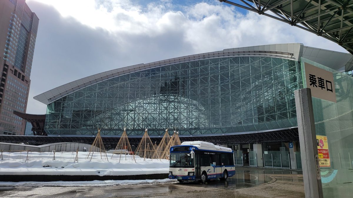 A curved glass station dome with snow on the ground and a bus in front