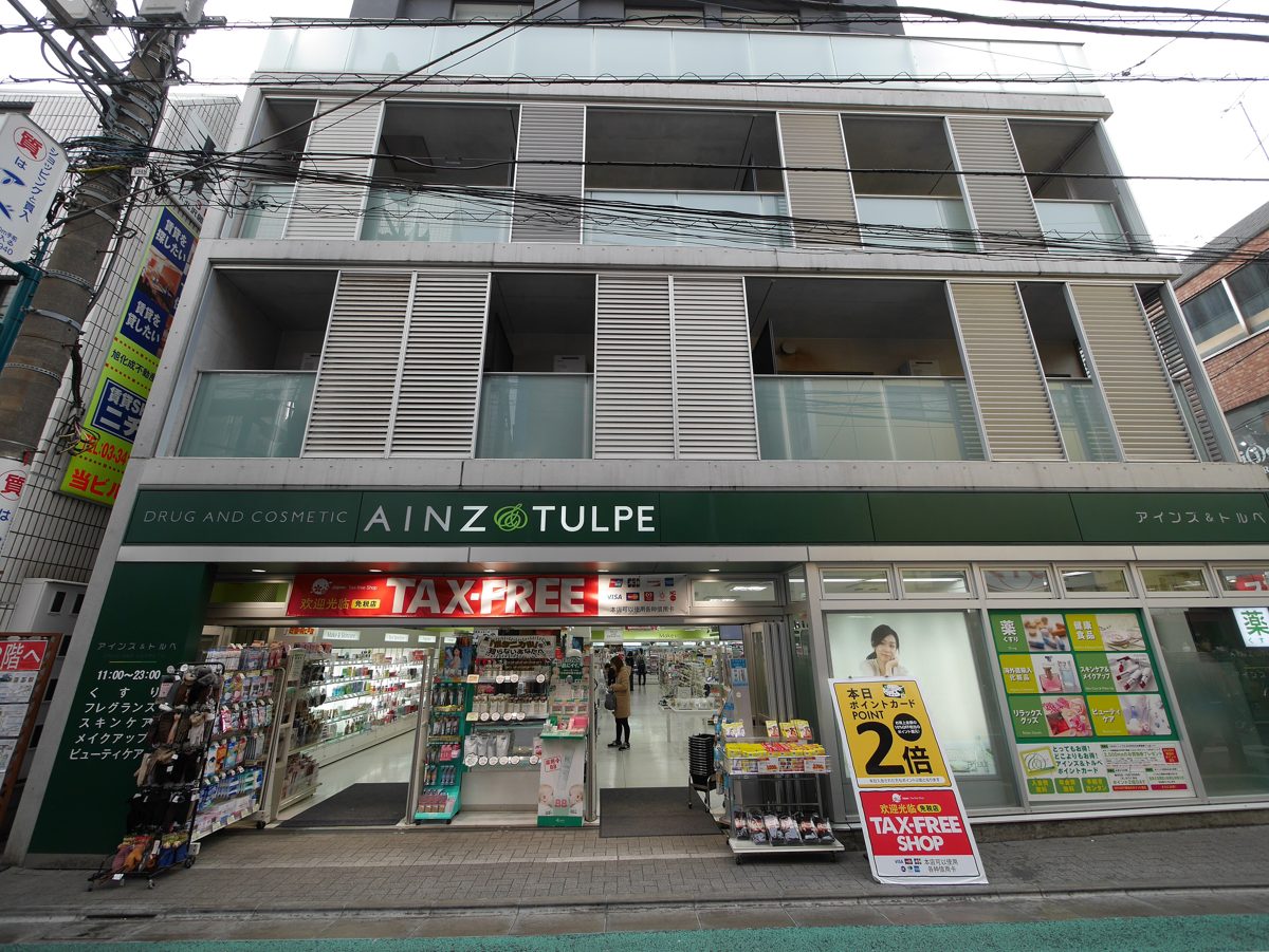 An Ainz & Tulpe drug and cosmetics store front with a red TAX-FREE banner and a tax-free shop stand sign