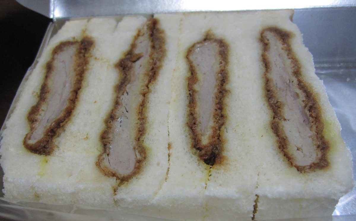Four slices of katsu sandwich with dark sauce between soft white bread
