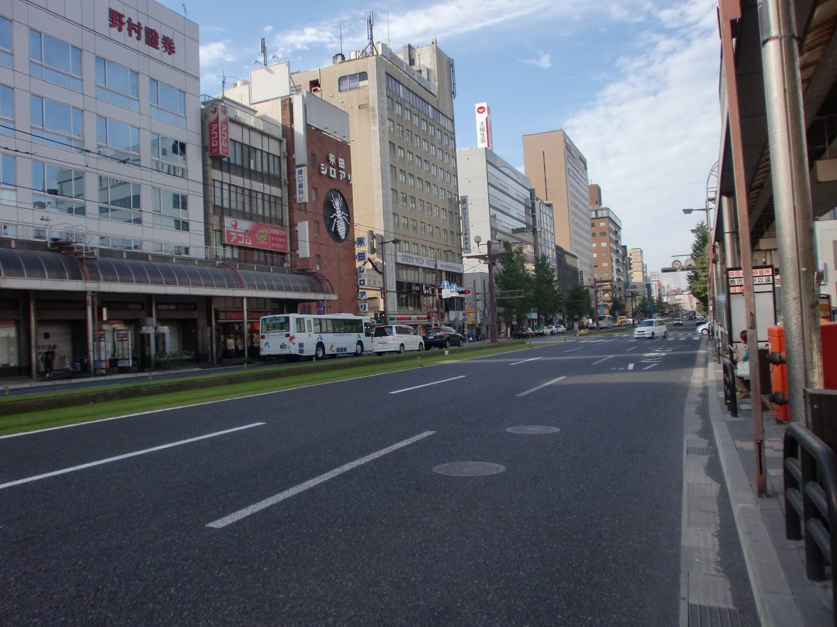 A wide city street lined with shops and office buildings in Tenmonkan, Kagoshima