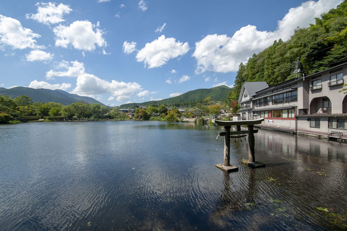 A calm lake with a small torii gate standing in the water under a blue sky