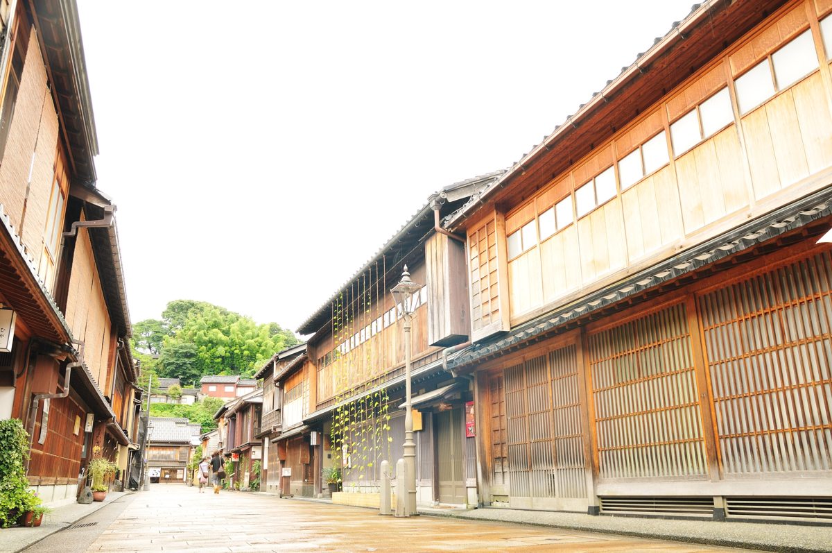 A stone-paved street lined with two-story wooden houses with latticed fronts