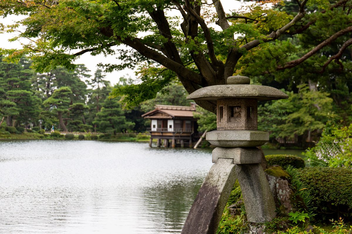 Stone lantern with two legs beside a pond in Kenroku-en garden