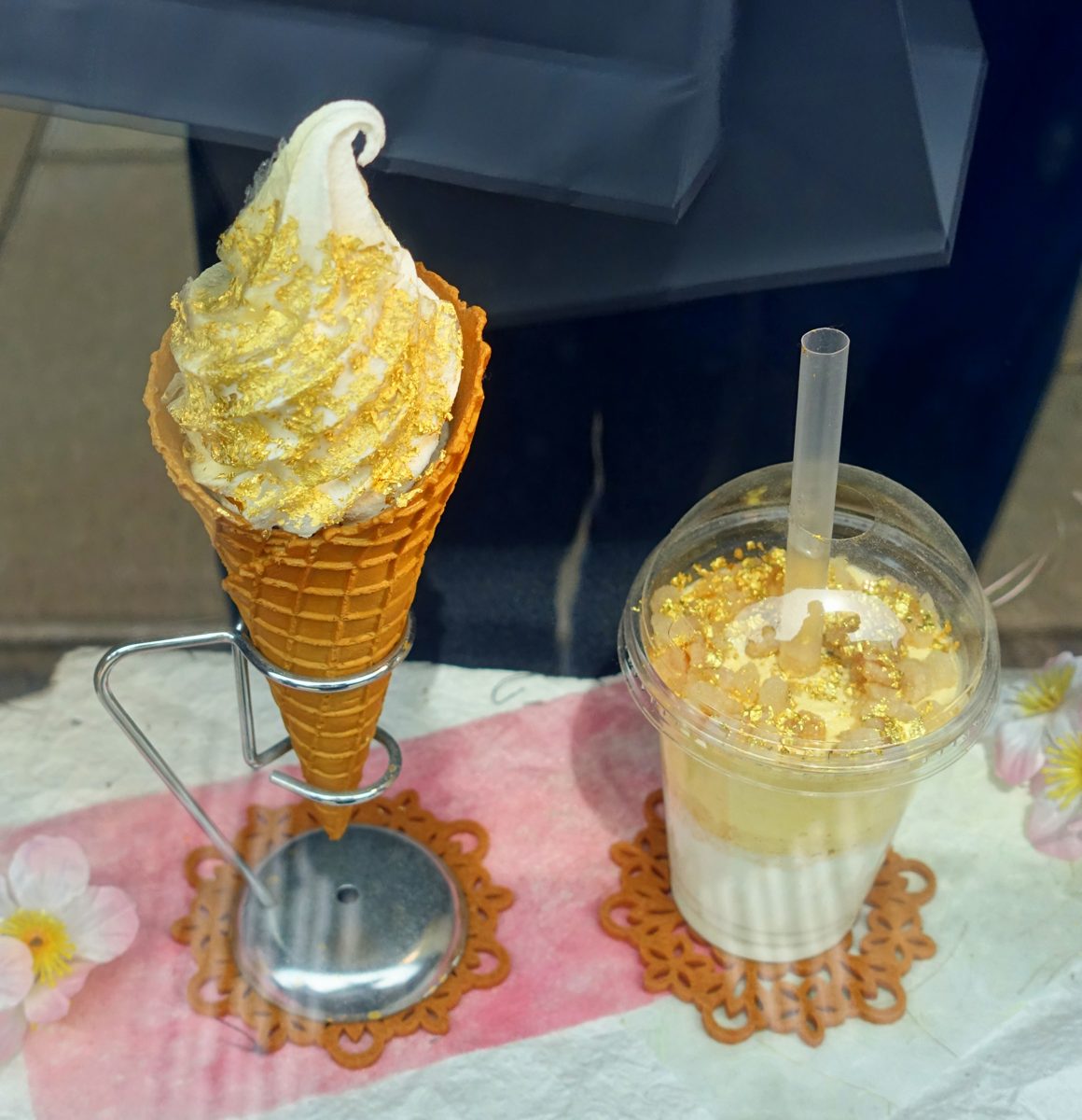 Soft serve ice cream cone and a drink topped with gold leaf on display