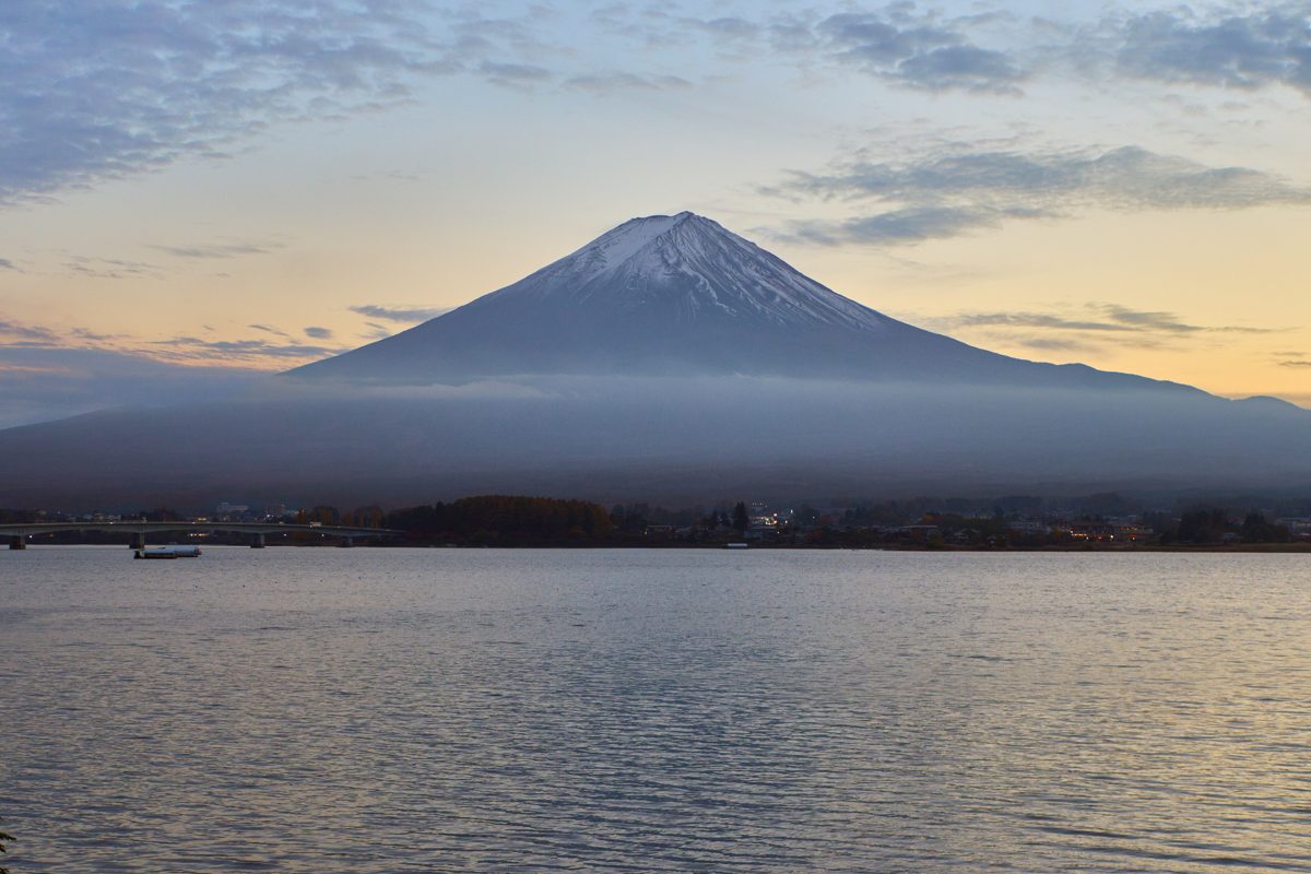 Snow-capped Mount Fuji above a calm lake at dawn