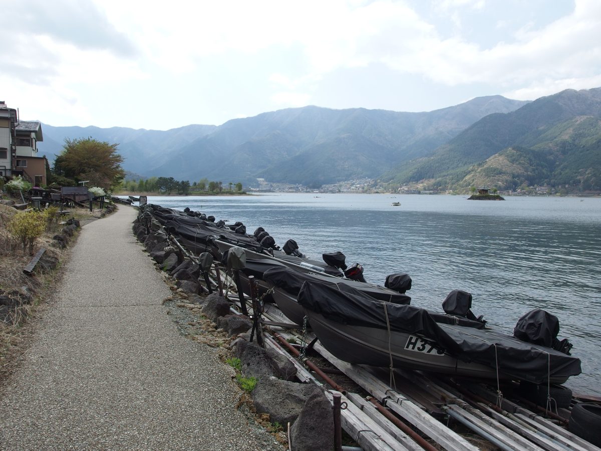 A footpath along the shore of Lake Kawaguchi with covered boats moored beside it