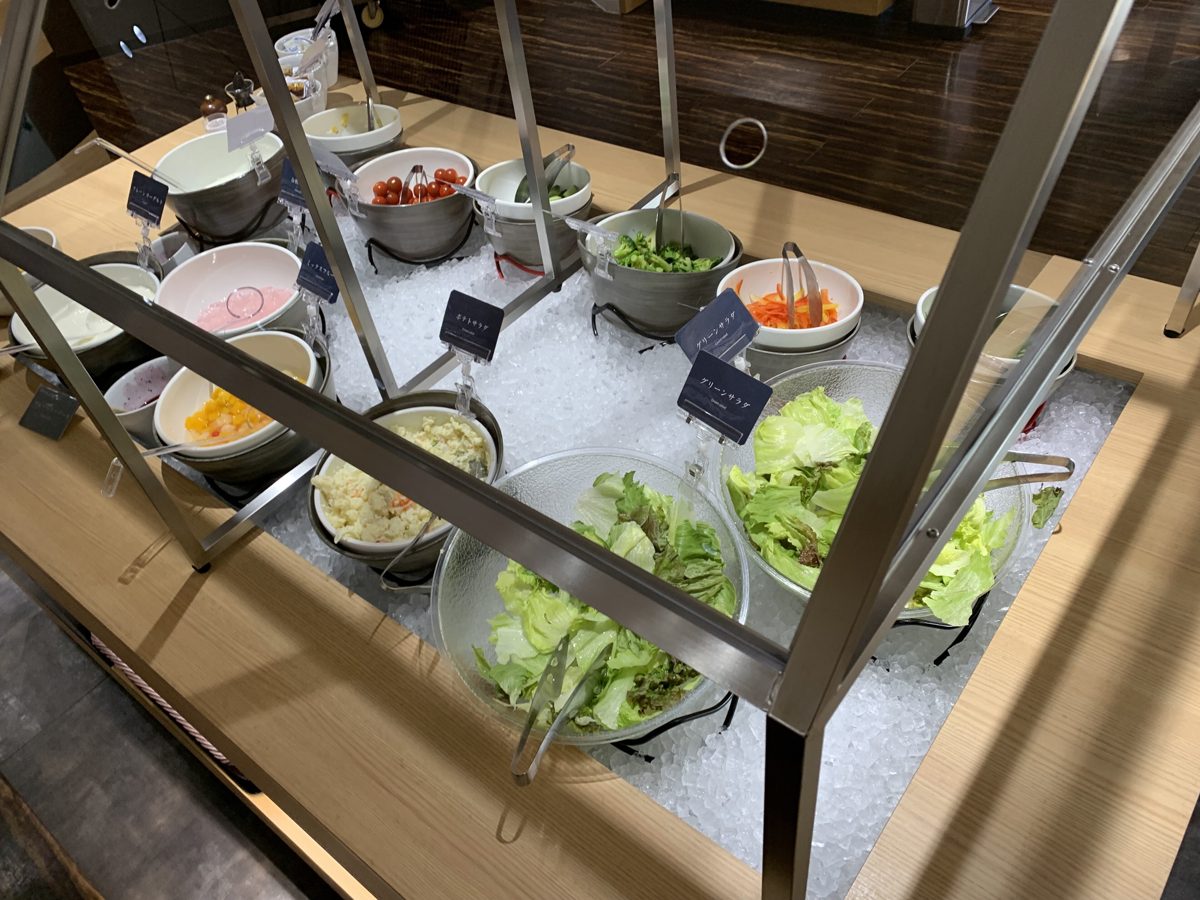 A salad bar of lettuce, tomatoes, potato salad and other dishes in bowls set on ice