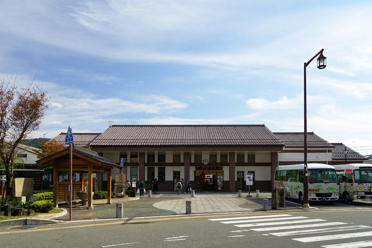 Kinosaki Onsen Station building with buses parked in front under a blue sky