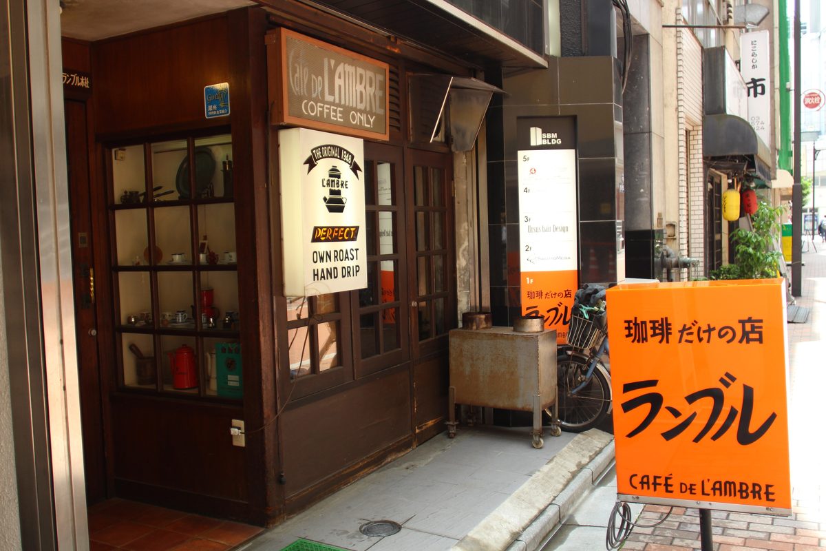 The wooden storefront of Cafe de L’ambre in Ginza with an orange sign in Japanese