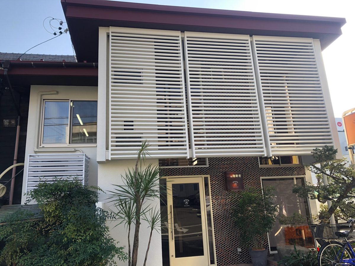 A two-story house with white louvered shutters and a tiled entrance, home to a Coffee-Kan branch