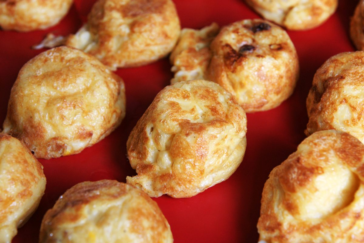 Close-up of soft, golden round egg dumplings on a red plate