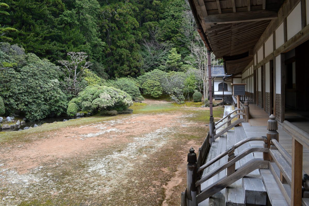 A moss and gravel courtyard garden beside a wooden temple veranda