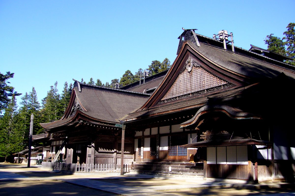 The large main hall of Kongobuji with a dark tiled roof under a blue sky