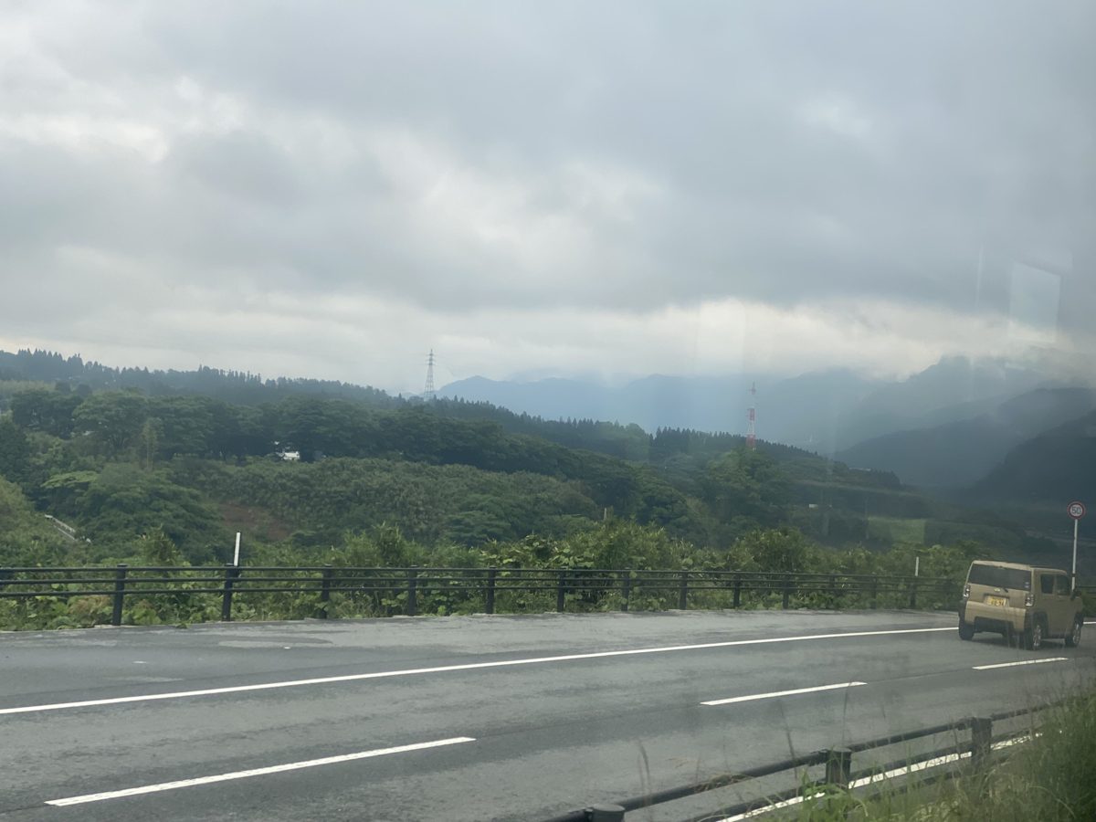 A two-lane road through green hills under a cloudy sky