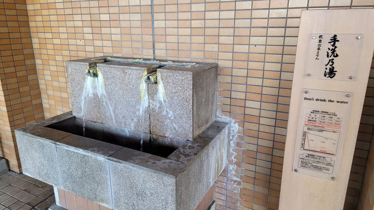 A stone spout pouring hot-spring water inside Kusatsu Onsen Bus Terminal