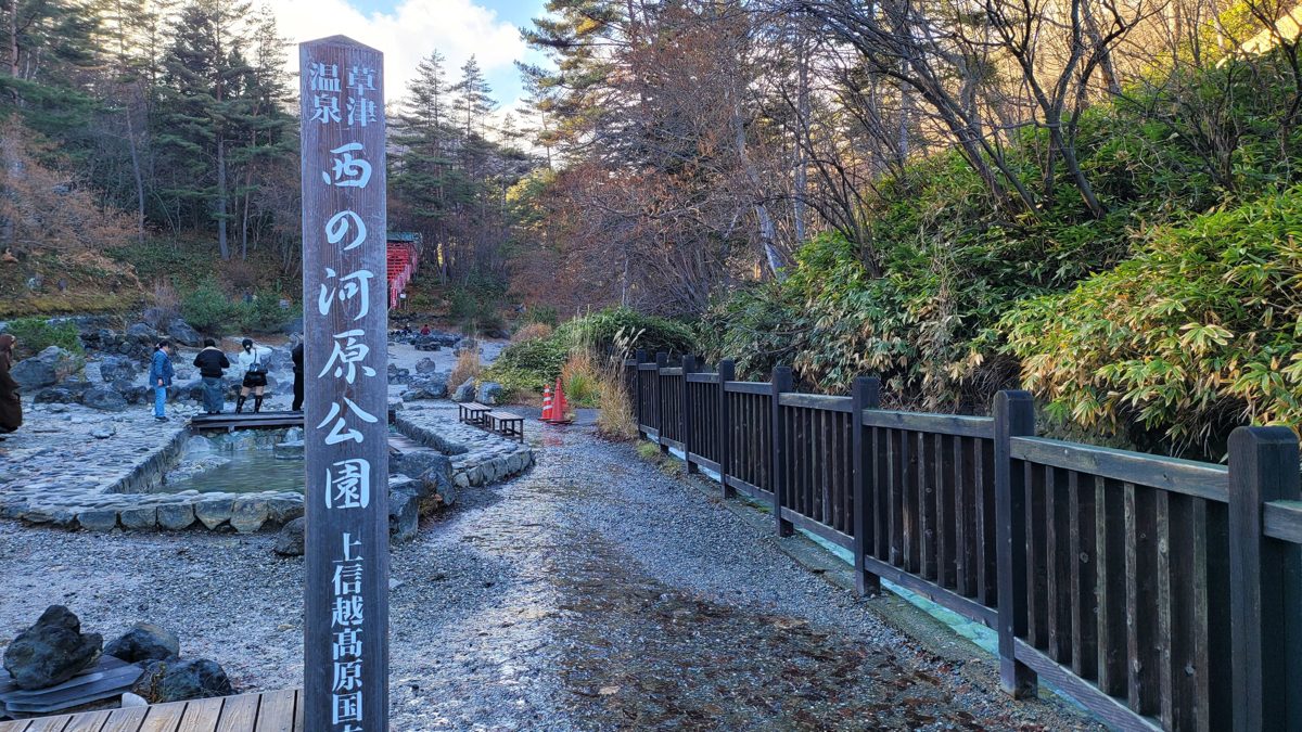 Sainokawara Park in Kusatsu Onsen with a stone path, pools and autumn trees