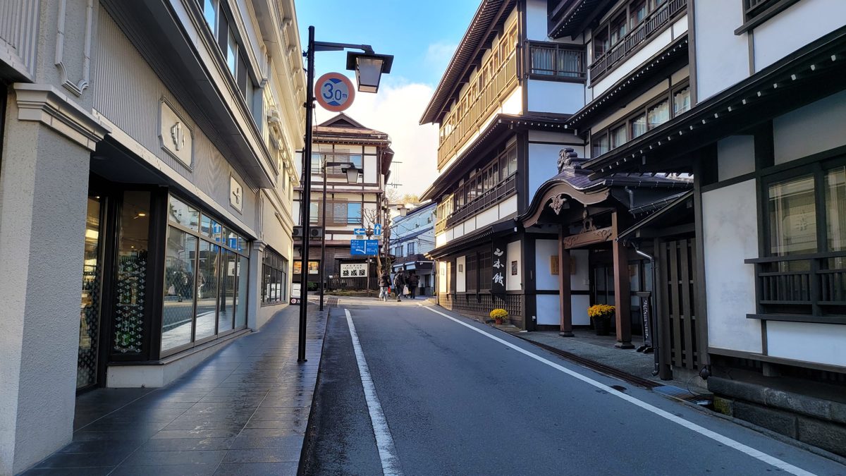 A quiet street of inns and shops in Kusatsu Onsen on a sunny day