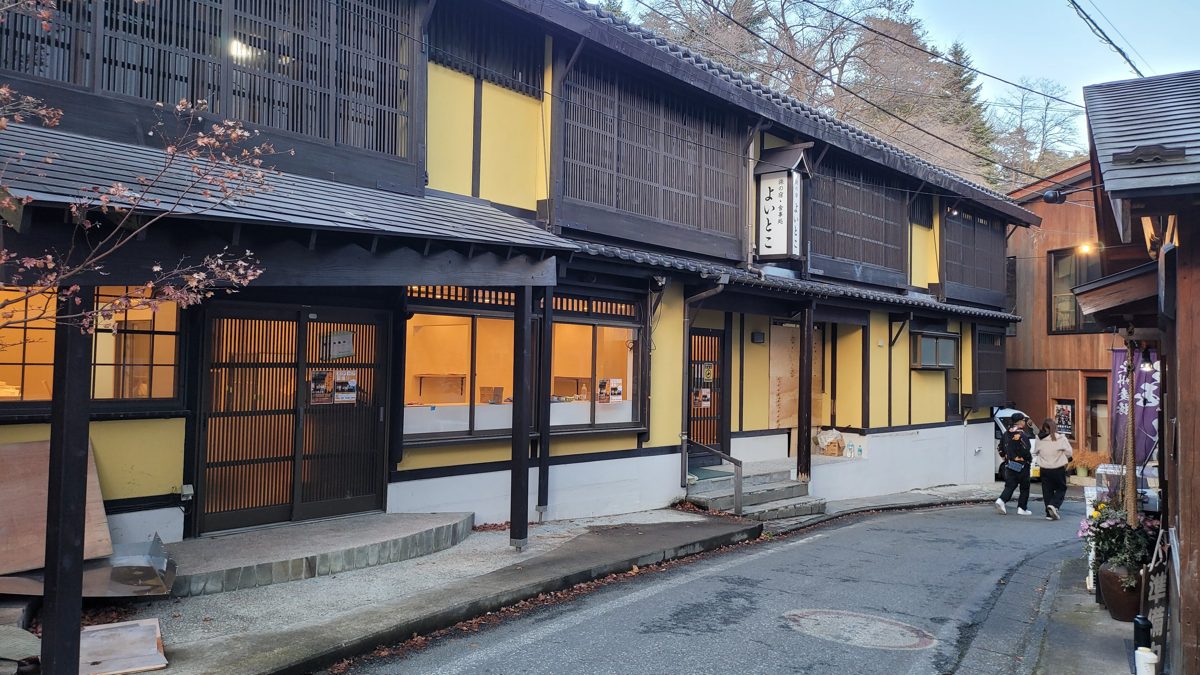 Old wooden buildings with lit windows along a street in Kusatsu Onsen