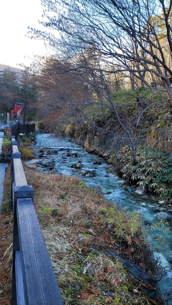 A stream running past autumn trees and a walking path in Sainokawara Park