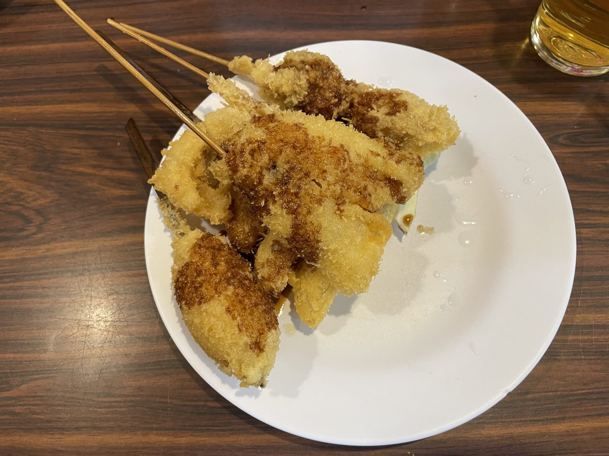 A plate of breaded kushikatsu skewers with sauce on a wooden table