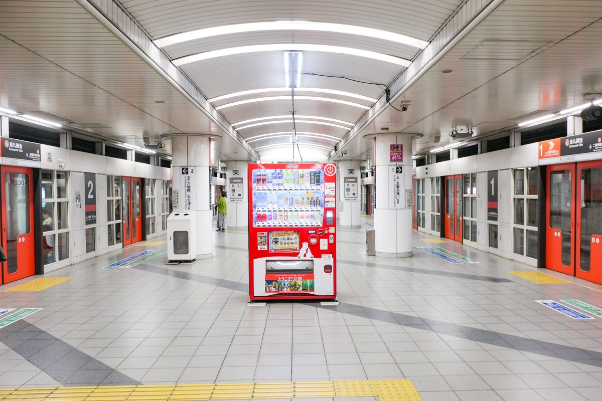A subway platform with platform doors and a red vending machine