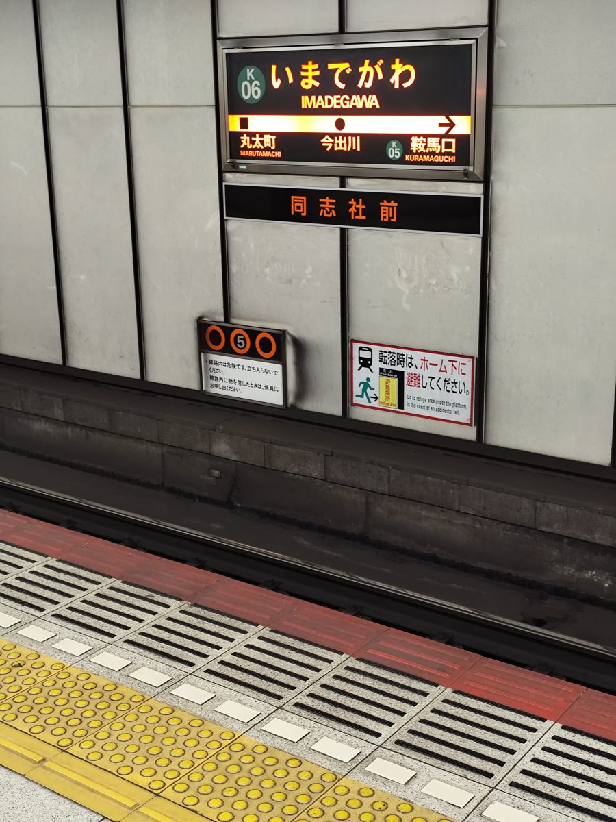 A subway platform with a station name sign for Imadegawa above the platform edge