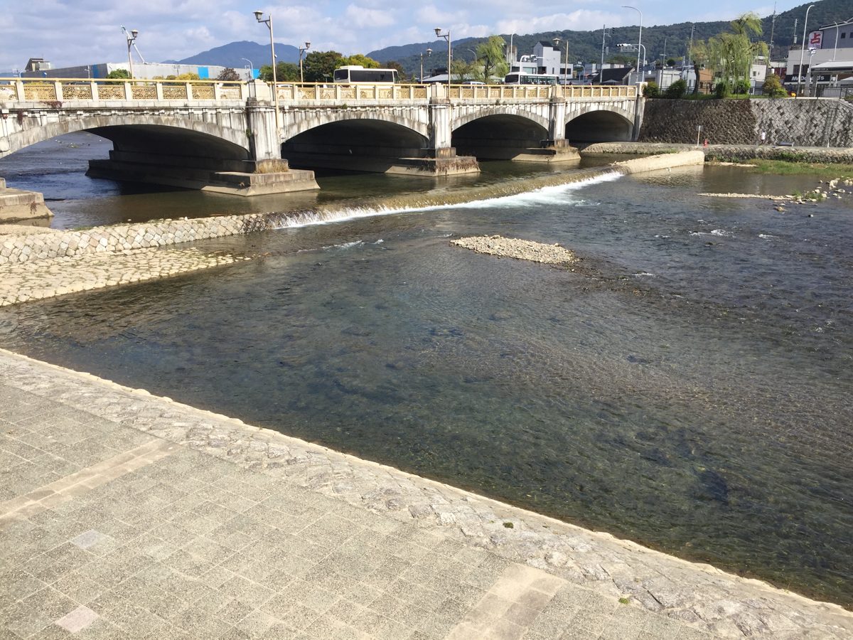 Shichijo Bridge, a stone arch bridge over the shallow Kamo River in Kyoto, on a sunny day