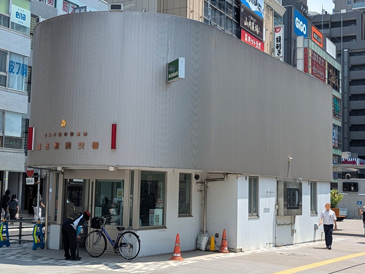 A koban police box with a curved silver facade in front of Chofu Station, Tokyo