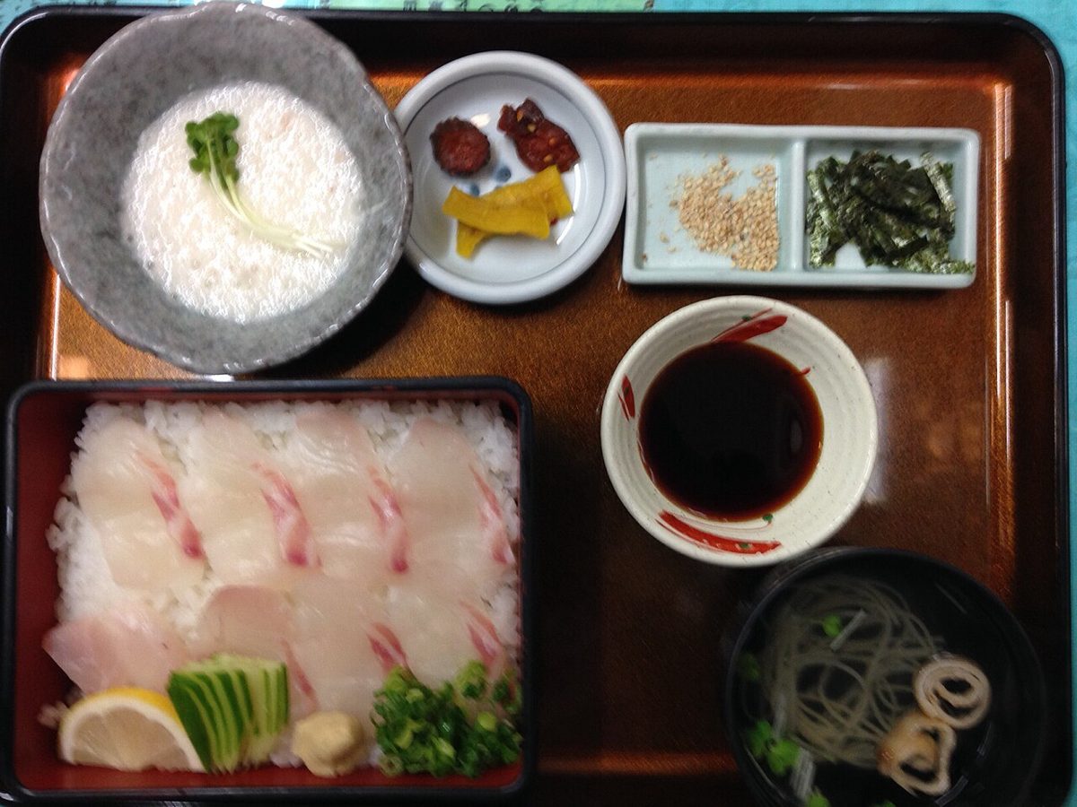 A lacquer tray with raw sea bream slices on rice, sauce and side dishes