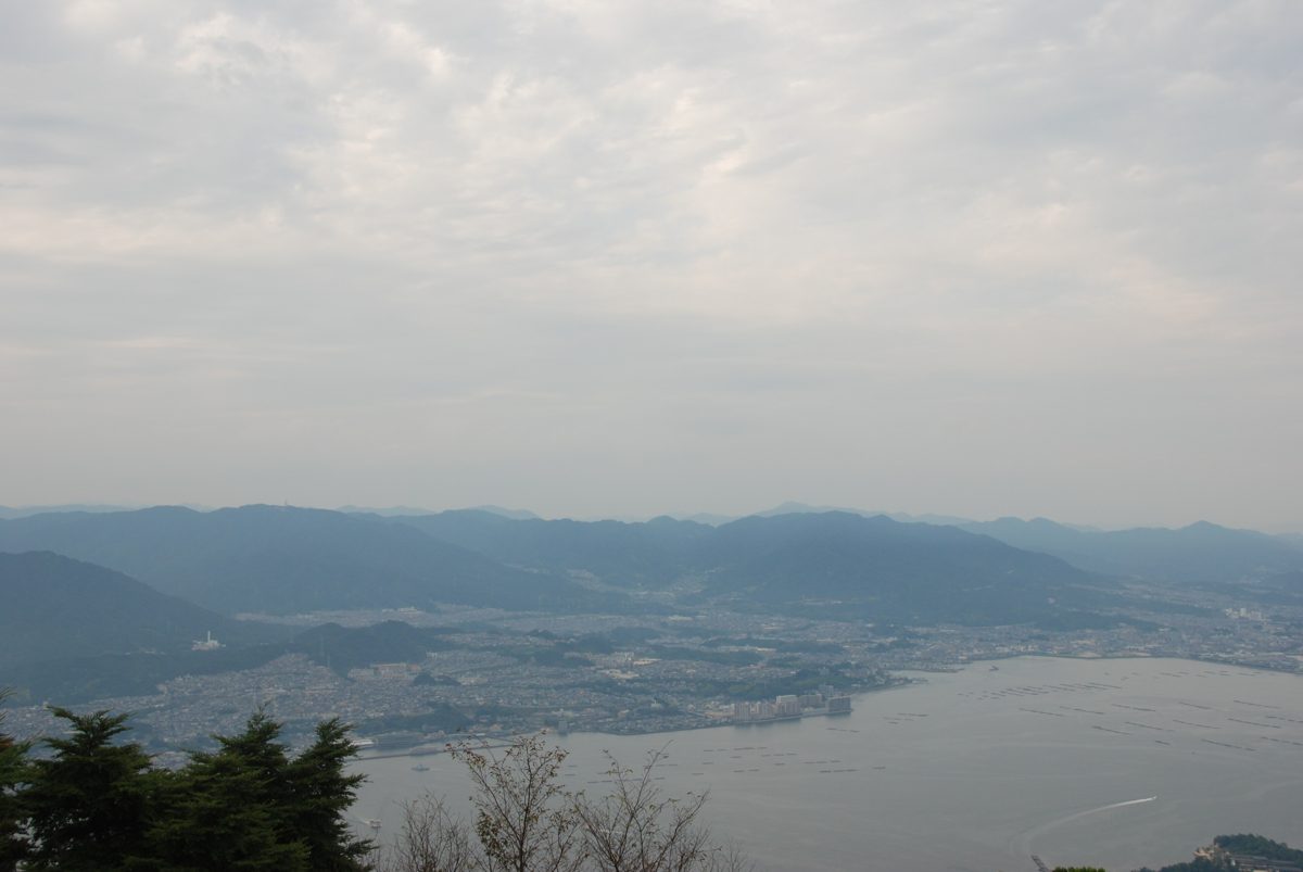 A hazy view from a mountaintop over the sea, oyster rafts and the city on the mainland